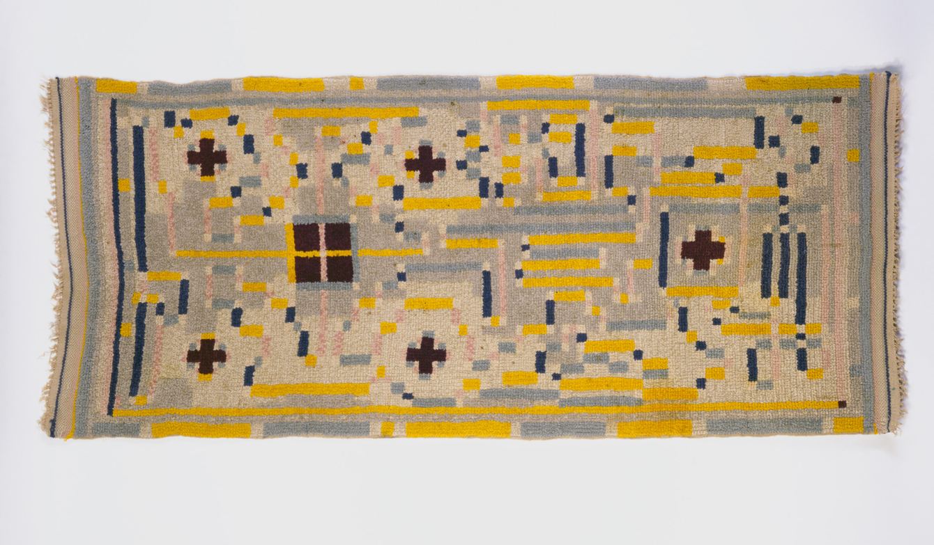 Foto eines Bildtteppichs von Johannes Itten. Farben Gelb dunkelblau, pastellgelb, alles geometrische Formen.