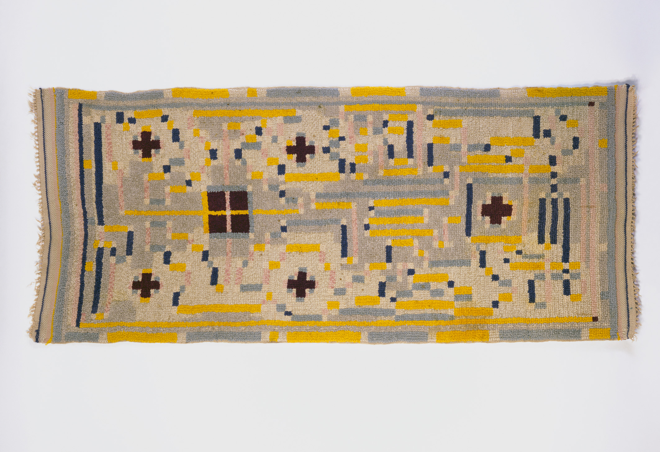 Foto eines Bildtteppichs von Johannes Itten. Farben Gelb dunkelblau, pastellgelb, alles geometrische Formen.