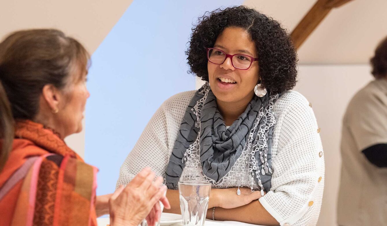 Zwei Personen im Gespräch an einem Stehtisch an der Präsident*innenkonferenz von Agile. Die Szene wirkt wie ein informelles Gespräch bei einer Veranstaltung oder einem Netzwerktreffen.