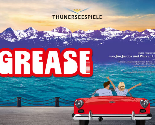 Im Vordergrund steht ein rotes Cabriolet, von hinten zu sehen. Darin sitzen zwei Personen, die fröhlich die Arme heben, als würden sie den Moment feiern. Vor ihnen glitzert der Thunersee in kräftigem Türkis. Dahinter ragen die verschneiten Alpen in die Höhe, violett getönt wie ein Bühnenhintergrund kurz vor der Premiere. Oben im Bild prangt das Logo der Thunerseespiele. Links steht gross ‹GREASE› in roter Schrift mit einem stilisierten Kamm. Die Szene wirkt wie ein Versprechen auf Sommer, Musik und eine Prise Rock’n’Roll.