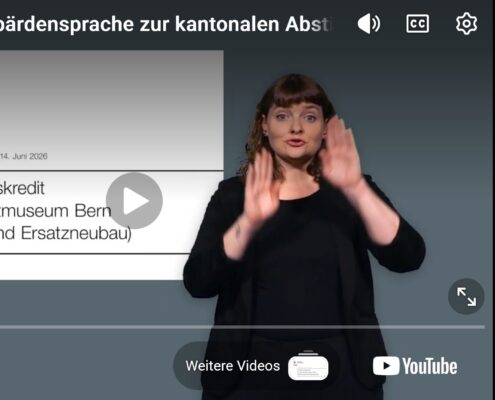 Screenshot eines Erklärvideos des Kantons Bern zur kantonalen Abstimmung vom 14. Juni 2026. Rechts im Bild steht eine Gebärdensprachdolmetscherin vor dunkelgrauem Hintergrund und übersetzt den Inhalt in Gebärdensprache. Sie trägt dunkle Kleidung und ist mit erhobenen Händen mitten in einer Gebärde zu sehen. Links ist die eingeblendete Titelfolie des Videos sichtbar mit dem Logo des Kantons Bern und dem Titel «Projektierungskredit für das Kunstmuseum Bern (Sanierung und Ersatzneubau)». Oben ist die Videoüberschrift «Erklärvideo in Gebärdensprache zur kantonalen Abstimmung» eingeblendet. Unten sind die typischen Bedienelemente eines YouTube-Videos mit Fortschrittsanzeige sichtbar.