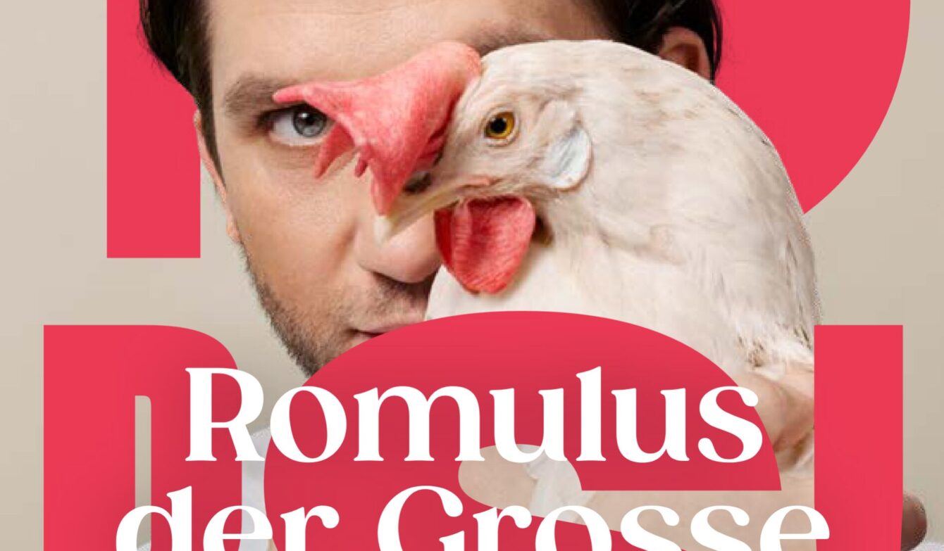 Nahaufnahme: Ein Auge eines Menschen blickt frontal, daneben überlappt der Kopf eines weissen Huhns mit rotem Kamm; im Hintergrund grosse rote Formen und der weisse Schriftzug «Romulus der Grosse».